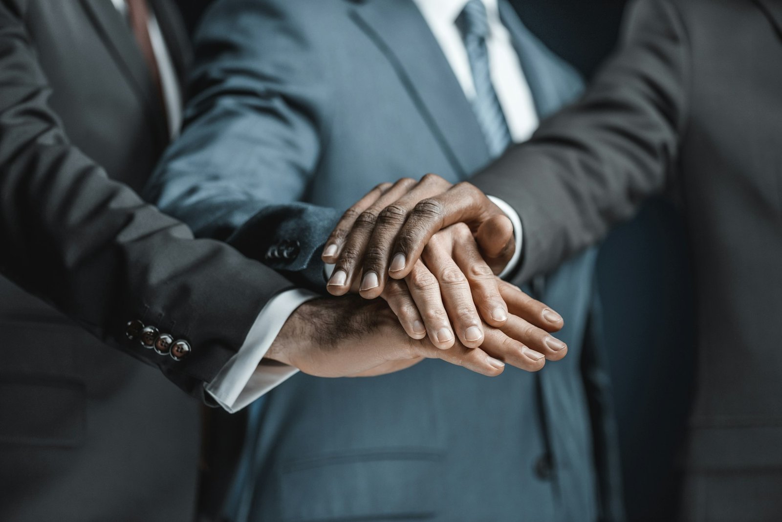 cropped shot of multiethnic group of businessmen holding hands together